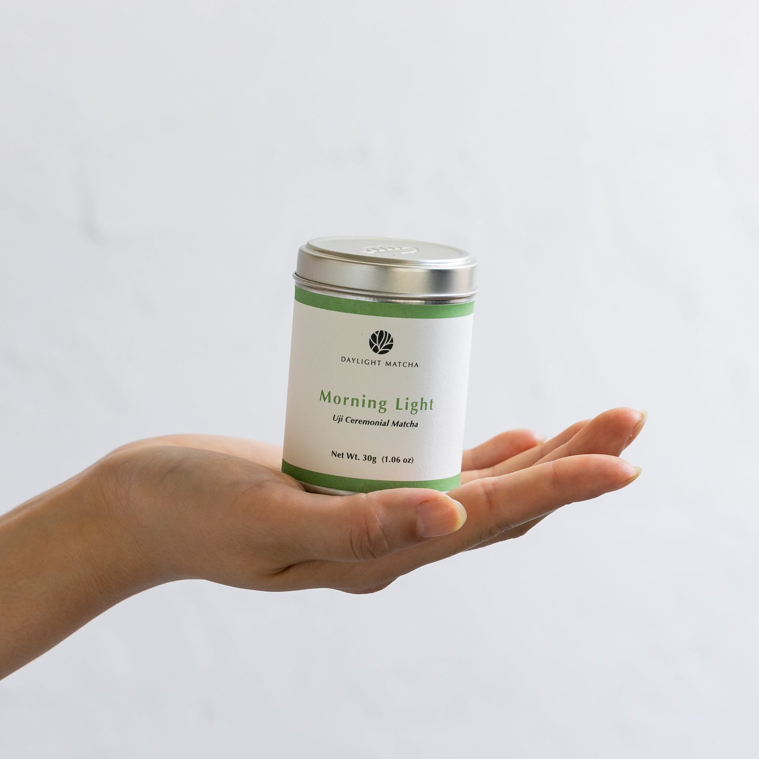 Hand holding a 'Morning Light' tea canister against a plain background